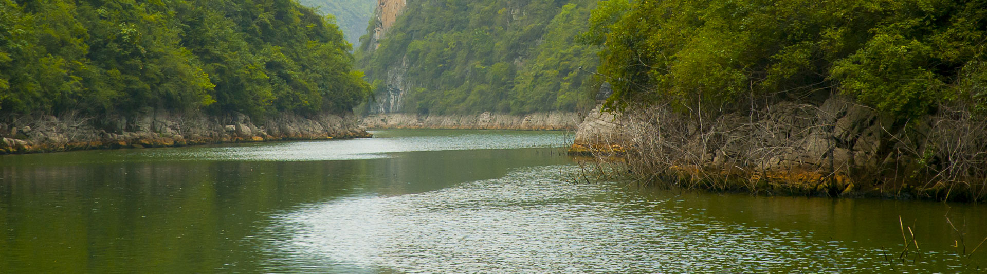Calm green river winding between forested limestone banks