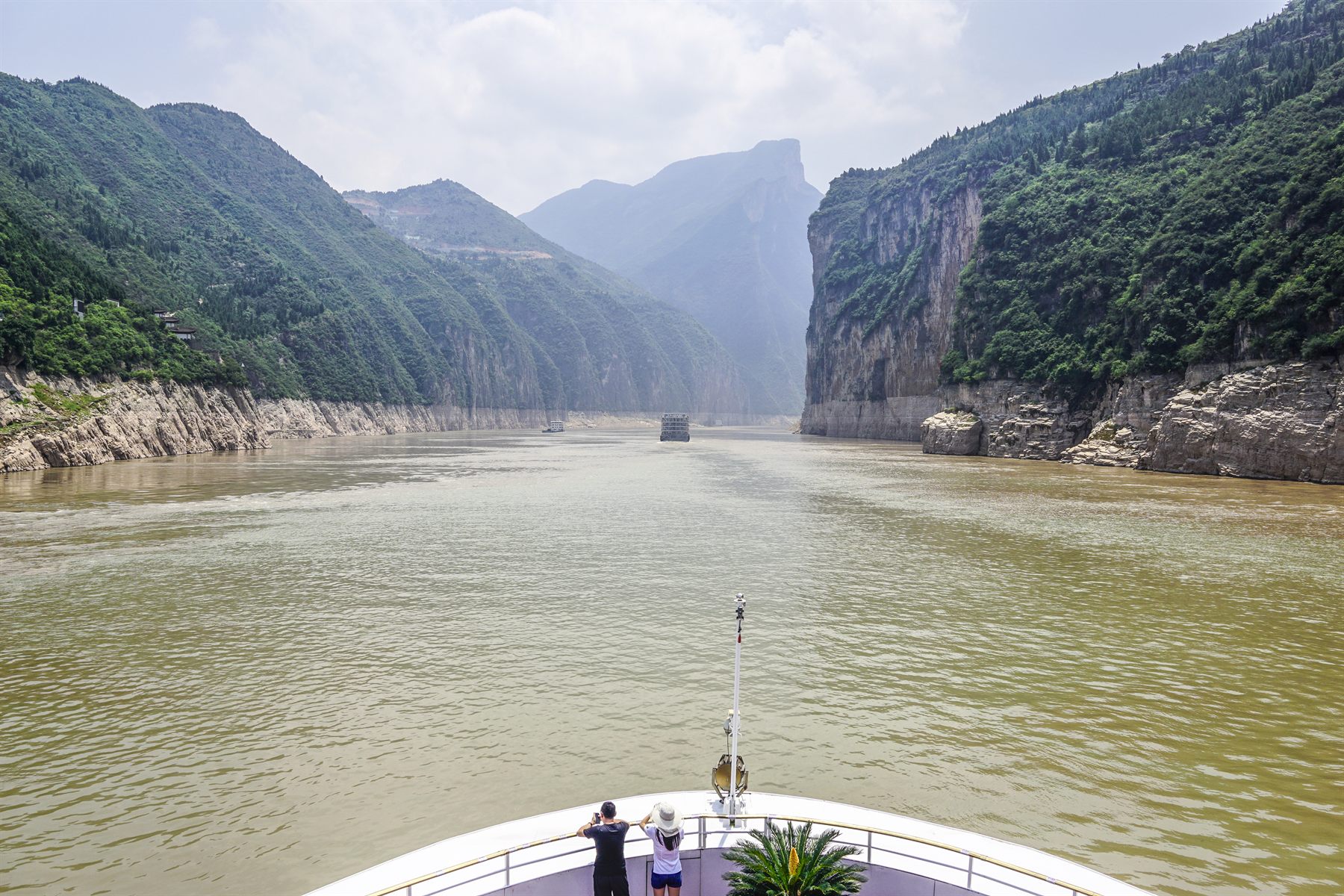 Passengers on the bow of a cruise ship heading into a steep Three Gorges canyon